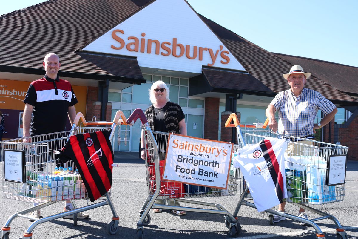 Three volunteeers stand outside Bridgnorth Sainsbury's in front of food trolleys